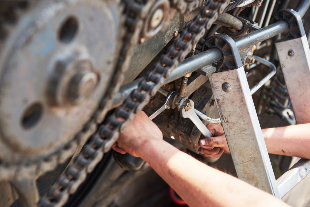 Mechanik dokonujący naprawy maszyny Bomag w terenie, używający bomag części zamienne podczas serwisu sprzętu.