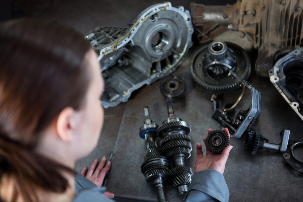 Kobieta mechanik sprawdza auxiliary engine spare parts – koła zębate i łożyska rozłożone na stole w warsztacie