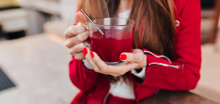 Kobieta trzymająca w dłoniach szklankę czerwonego soku likopenowego